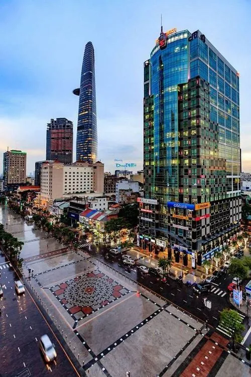 Toàn cảnh góc cao nhìn xuống phố đi bộ Nguyễn Huệ lúc chiều muộn với dòng xe ken dọc hai bên và các tòa tháp kính hiện đại tạo khung cảnh trung tâm Sài Gòn cực sang trọng