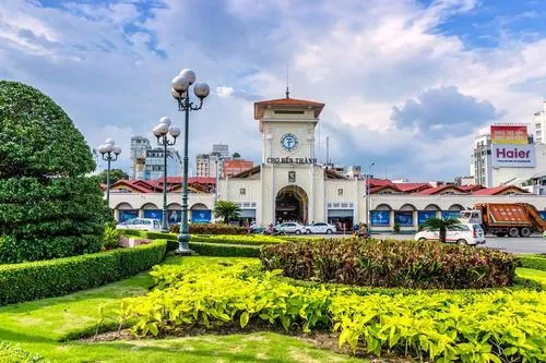 Một người bán trái cây đẩy xe dọc con đường gần chợ, nắng sớm chiếu xiên qua tán cây làm mọi thứ trở nên nhẹ và chậm hơn thường ngày