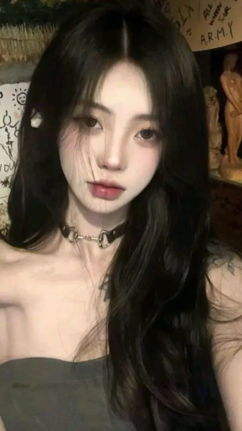 Gái xinh tóc đen dài vai trần đeo choker bạc nhìn thẳng camera son môi đỏ nổi bật trong ánh sáng studio ấm áp toát lên thần thái ngầu cá tính mạnh mẽ.