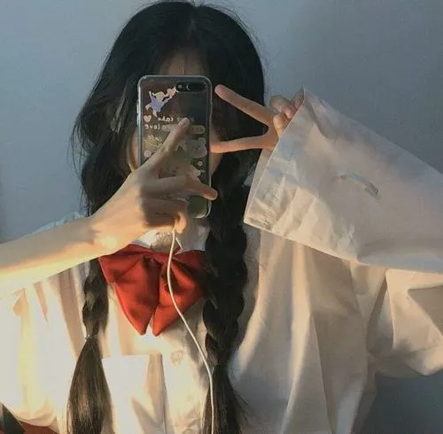 Ảnh selfie ẩn danh áo sơ mi trắng oversized buộc nơ đỏ tóc dài dùng điện thoại che mặt phong cách tinh tế.