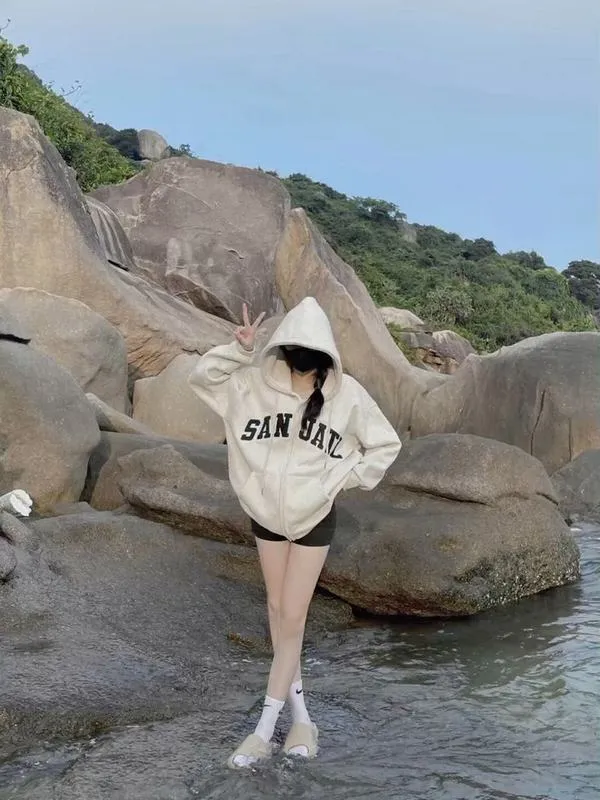 Hot girl mặc bikini trắng ngồi trong nước nông che mặt bằng tay tóc dài ướt át sóng vỗ quanh.