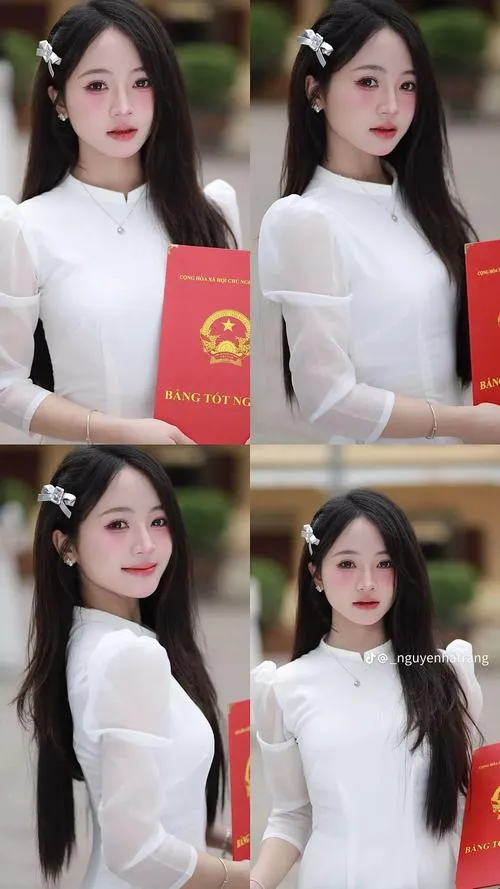 Gái xinh mặc áo dài trắng đang mỉm cười nhẹ tay khẽ vuốt tóc giữa vườn cây xanh làn da căng mịn toát lên nét thiếu nữ mười tám trong trẻo.