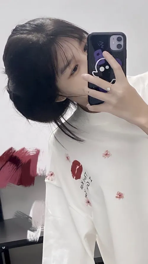 Ảnh hot girl giấu mặt tóc ngắn cá tính áo trắng in hình cầm điện thoại sticker che mặt vui tươi.