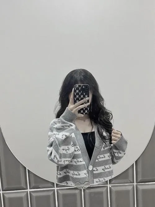 Mặc áo khoác caro tóc dài cầm điện thoại lưới che mặt trong góc phòng.