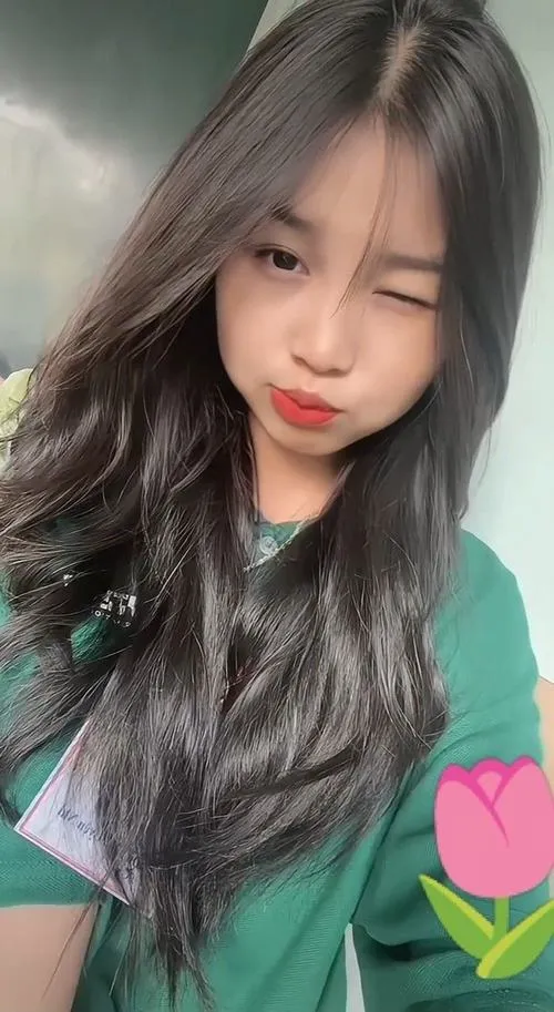Gái xinh mái tóc dài đen mặc áo xanh nghiêng đầu chúm môi nhẹ mắt hơi nheo trông ảnh gái xinh ngọt ngào lắm.