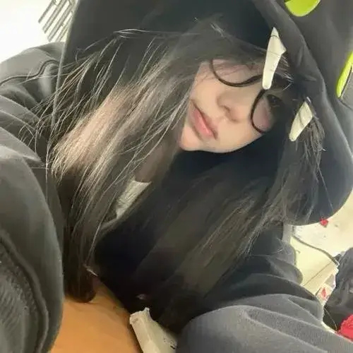 Gái xinh đội mũ len che một phần mặt, tóc đen dài, hoodie rộng trong phòng tối.