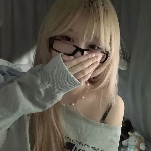 Hot girl dùng tay che mặt nghiêng người, tóc dài highlight, áo len xám trong phòng.