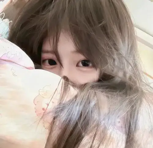 Hot girl nằm nghiêng ôm gối che mặt một bên, tóc đen dài, áo trắng ren trong phòng ngủ.