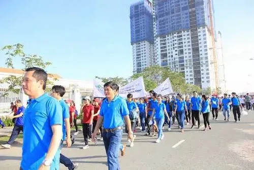 Tập thể nhân sự đứng thành hàng ngoài trời dưới nắng nhẹ, áo xanh đồng bộ nổi bật giữa không gian rộng tạo cảm giác trẻ trung và đoàn kết