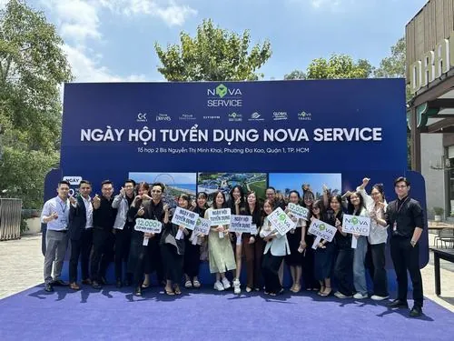 Hàng nhân viên đứng thẳng trước backdrop sự kiện ngoài trời, vest tối màu kết hợp sơ mi sáng tạo nên tổng thể đồng bộ của nhân sự tập đoàn Nova