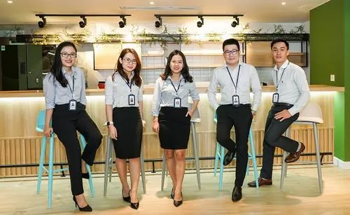 Ảnh chuyên viên nhà đất Novaland bước đi tại khu trưng bày dự án với dáng vẻ tự tin, đồng phục sáng màu và phong thái phục vụ rất chỉnh chu