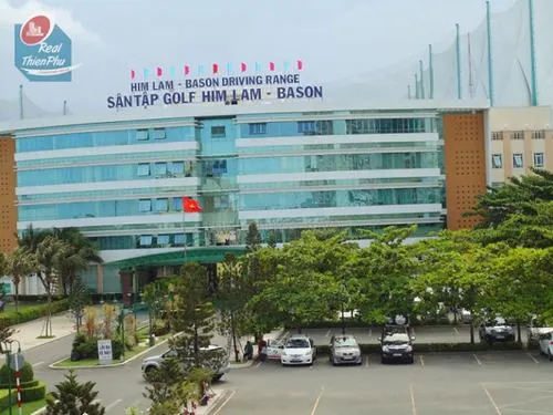Ảnh check in sân golf Him Lam ghi lại mặt tiền khu nhà điều hành hiện đại với bảng hiệu nổi bật phía trước, mang cảm giác chuyên nghiệp và chỉn chu của một sân golf quy mô lớn