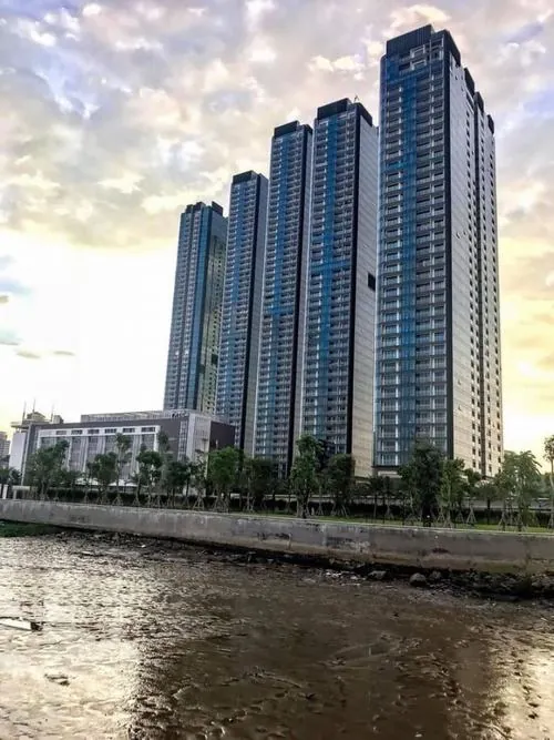 ảnh căn hộ dãy tháp kính cao vút sát mép sông phản chiếu ánh chiều nhẹ, mặt nước êm và không gian Vinhomes Golden River nhìn rất sang trọng