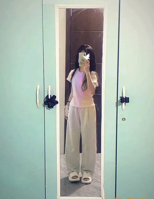 Cô nàng tóc ngắn nhuộm highlight mặc hoodie tối màu ngồi trên ghế sofa da dùng điện thoại che mặt nghiêng đầu nhẹ.