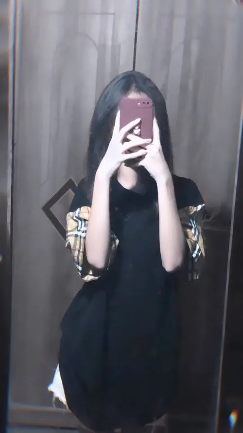 Hot girl mặc quần jeans ống rộng áo crop đen đứng ngoài ban công chiều hoàng hôn cầm điện thoại giấu mặt.