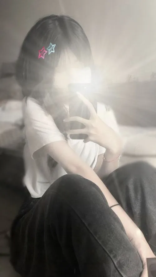 Ảnh hot girl giấu mặt mặc áo blouse trắng cổ V tóc uốn sóng đứng trong thang máy cầm điện thoại.