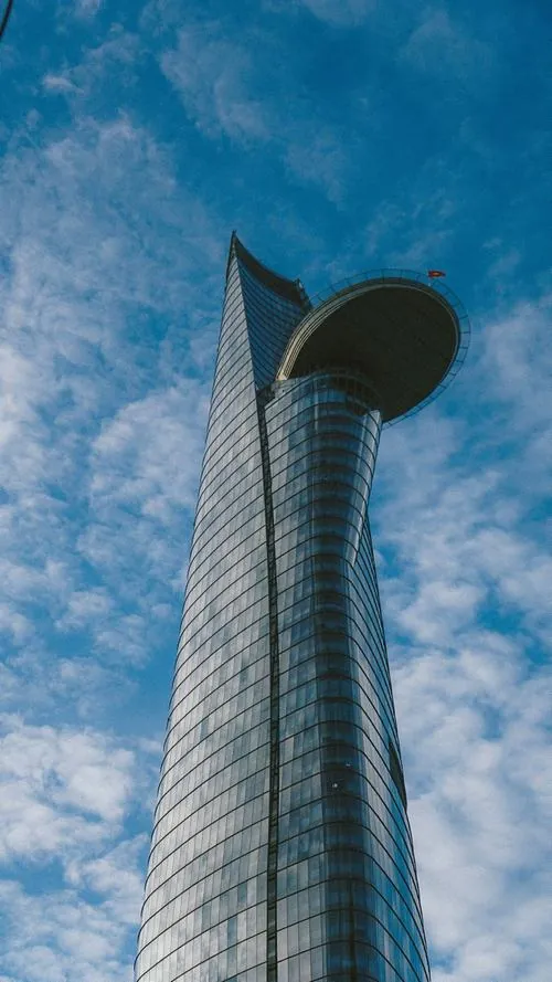 ảnh tháp tài chính Sài Gòn trong ánh sáng xanh buổi sáng sớm, tòa nhà nổi bật với đường nét mềm mại và lớp kính sáng phản chiếu rất đẹp