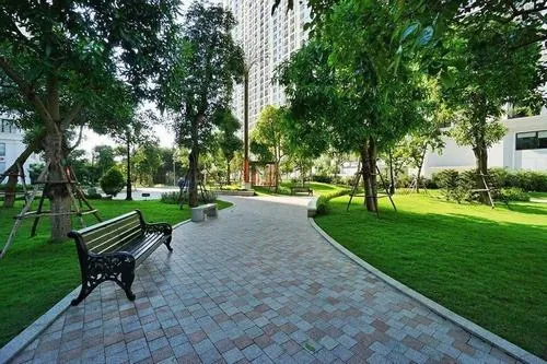 Cây cầu đỏ nhỏ bắc qua hồ, mặt nước yên phản chiếu cảnh xung quanh, tạo điểm nhấn nhẹ nhàng trong tổng thể công viên Landmark 81 xanh mát