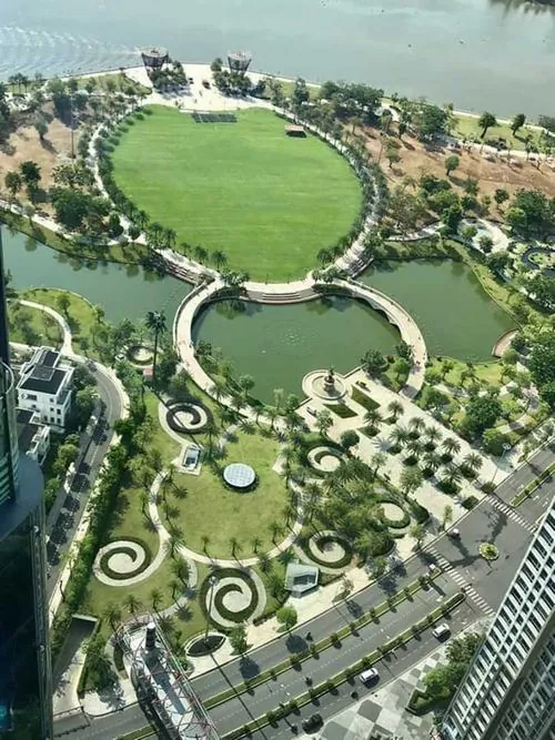 Khung hình nhìn từ trên cao ghi lại thảm cỏ rộng cùng hồ nước uốn lượn, các lối dạo xen kẽ tạo bố cục rõ ràng, gợi cảm giác thư giãn tại công viên Landmark 81 đẹp