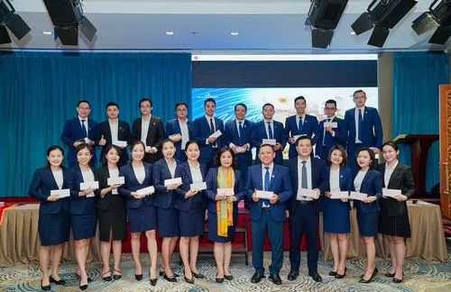 Ảnh công sở đẹp ghi lại khoảnh khắc dàn nhân viên đứng sát nhau tạo dáng tập thể, sắc xanh thương hiệu nổi bật trên nền sân khấu khiến tổng thể vừa đồng bộ vừa hiện đại