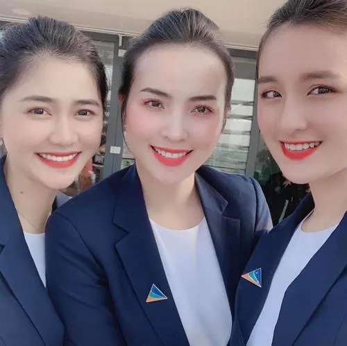 Ba nữ nhân viên trang điểm nhẹ nhàng đứng sát nhau mỉm cười trước ống kính, mái tóc buông gọn và blazer xanh khiến diện mạo thêm duyên dáng trong khung hình cận mặt