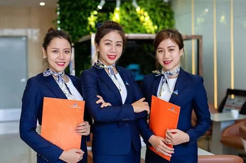 Ảnh gái xinh công sở ghi lại nhóm nữ nhân viên cầm tài liệu đứng trước quầy tiếp đón, đồng phục xanh navy phối khăn cổ tạo điểm nhấn mềm mại và chuyên nghiệp