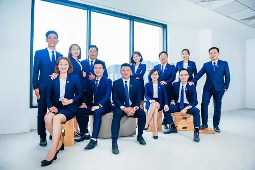 Dàn nhân viên nam nữ đứng thành cụm trước mặt kính văn phòng, ai cũng giữ tư thế thẳng lưng và nụ cười thân thiện đúng chất nhân viên kinh doanh hiện đại