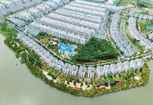 Ảnh đại đô thị nhìn xuống khu biệt lập với đường nội khu bao quanh hồ nhỏ, cây xanh phủ kín, các dãy nhà bố trí gọn gàng trong không gian sống xanh chuẩn nghỉ dưỡng