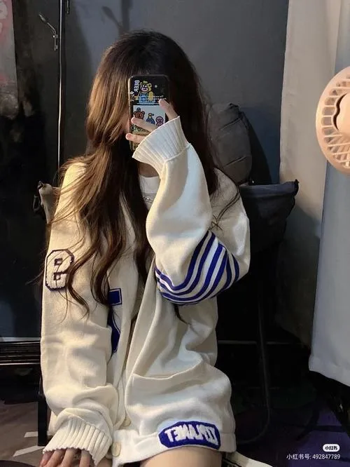 Thiếu nữ ẩn danh mặc áo hoodie oversize quần short denim nằm nghiêng trên thảm cầm điện thoại giấu mặt.