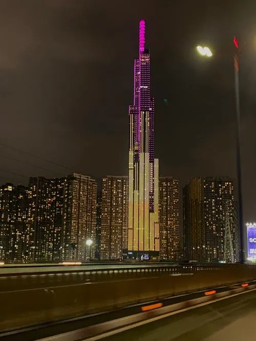 Góc chụp từ đường phố đông xe, Landmark 81 vươn lên phía xa như một cột mốc dẫn hướng giữa dòng chuyển động