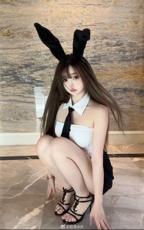 Mỹ nhân tóc đen dài ngồi trước gương mặc váy đen ren mỏng tai thỏ đen nhỏ tay cầm điện thoại selfie ánh mắt long lanh môi khẽ cười táo bạo thu hút.