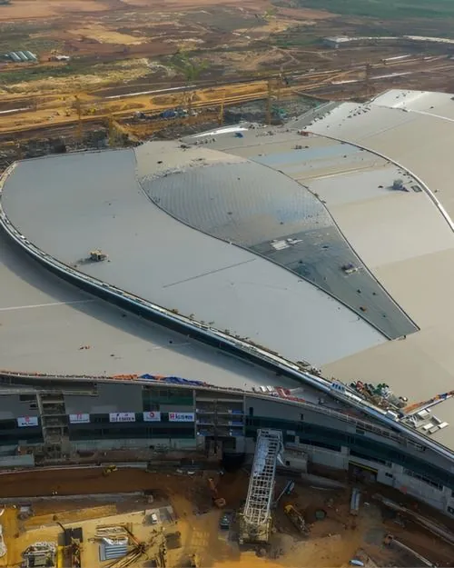 Ảnh đại công trường ghi lại khu vực nhà ga đang hình thành với kết cấu khung rõ rệt, bề mặt đất nâu và các tuyến đường tạm tạo nên bức tranh cửa ngõ bầu trời Long Thành khá sống động