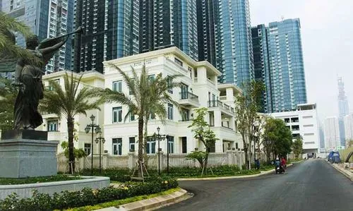 Một dãy nhà thấp tầng trắng sáng nằm giữa nhiều cây xanh, khung cảnh chung cư cao cấp Quận 1 mang vibe thư thái và sang trọng