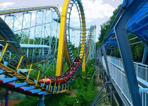 Một đường trượt vòng cung màu xanh vàng, người chơi ôm phao đôi lao xuống với biểu cảm vừa hồi hộp vừa thích thú