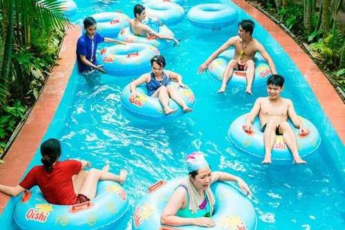 Trải nghiệm ở công viên nước Đầm Sen với máng trượt mở, người chơi nằm ngửa trôi xuống nước, ánh nắng chiếu lên tạo khung hình đẹp tự nhiên