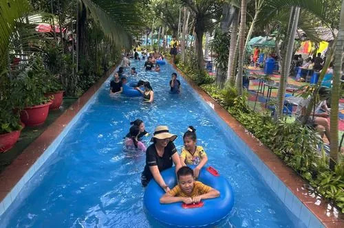 Không gian công viên nước Đầm Sen với đường trượt xanh dài xuyên qua hàng cây, góc chụp dọc tạo chiều sâu khá cuốn