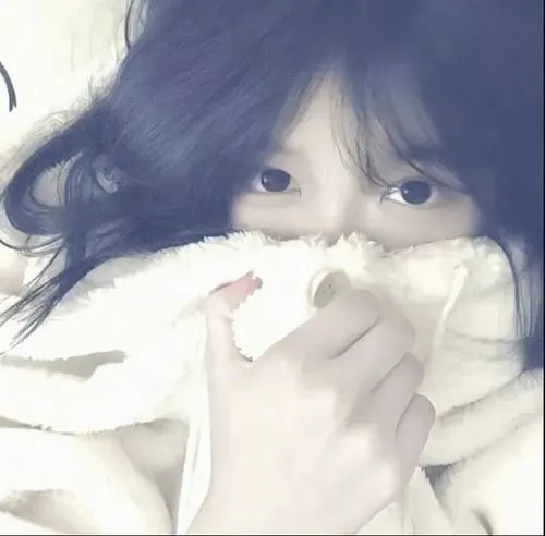 Thiếu nữ ẩn danh ngồi ghế sofa da cầm cốc trà sữa che miệng, tóc ponytail cao buộc nơ, áo hoodie crop khoe eo thon.