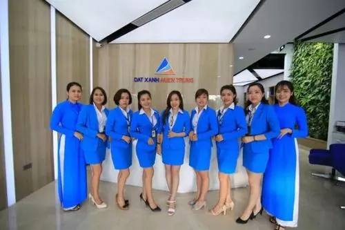 Khoảnh khắc công sở xinh xắn của nhóm nhân viên trẻ đứng quây thành vòng bán nguyệt, tay đặt trước người lịch sự và đồng phục xanh tạo nét đồng nhất rất đẹp mắt