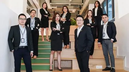 Ảnh nhân viên công sở Novaland tạo dáng trước backdrop sự kiện với vest đen đồng bộ, nụ cười tươi giúp khung hình thêm thân thiện