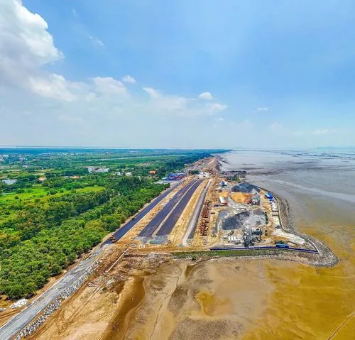 Ảnh Vinhomes Long Beach Resort thể hiện trục đường chính kéo dài ra phía biển, hai bên là nền đất đang hoàn thiện, ánh nắng chiếu xuống tạo cảm giác thoáng và rất thật