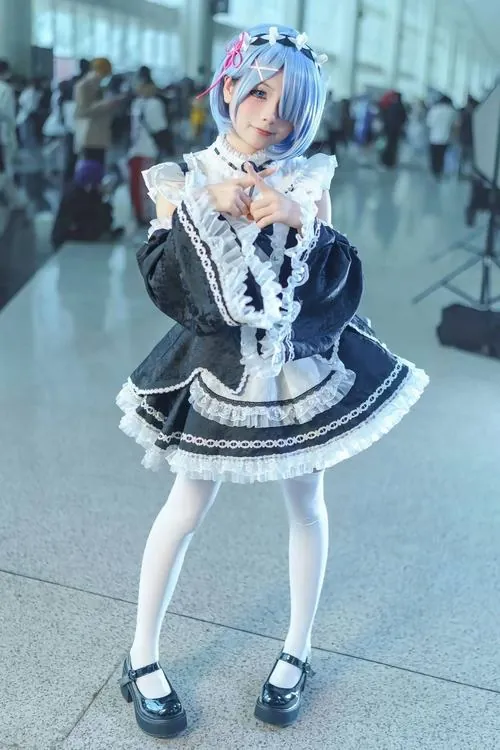 Cosplayer tóc xanh ngồi nghiêng dưới ánh sáng dịu, cổ áo ren trắng và đôi mắt biết nói tạo thần thái đỉnh cao.