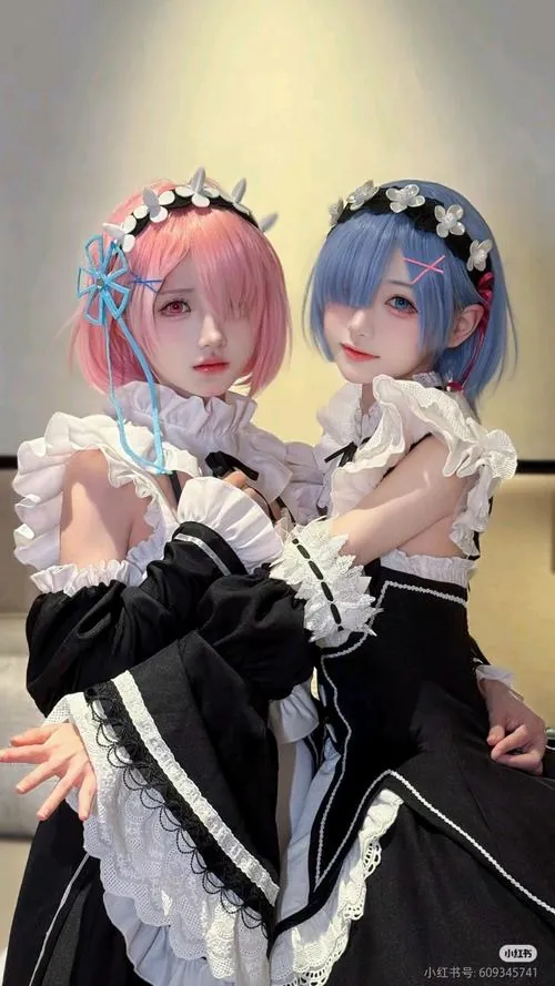 Hai cosplayer Ram và Rem ngồi cạnh nhau trong trang phục hầu gái, biểu cảm mềm mại tạo không khí anime rất ngọt.