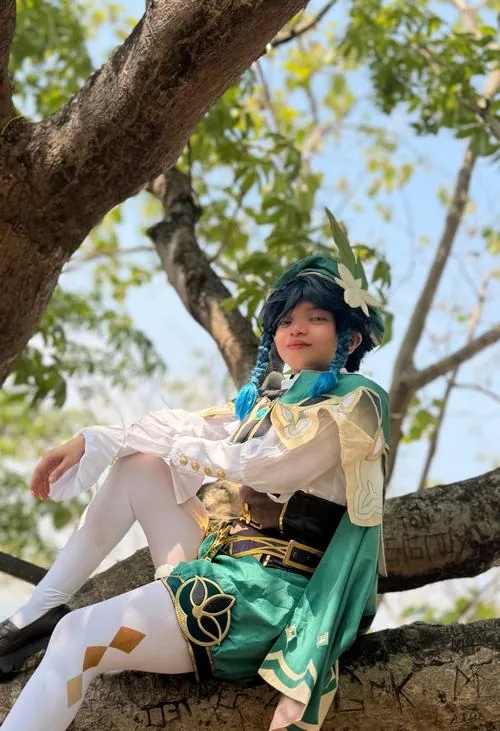Cosplayer ngồi trên cành cây trong rừng, tay giữ hạc cầm vàng tạo cảm giác như đang ngân giai điệu nhà thơ